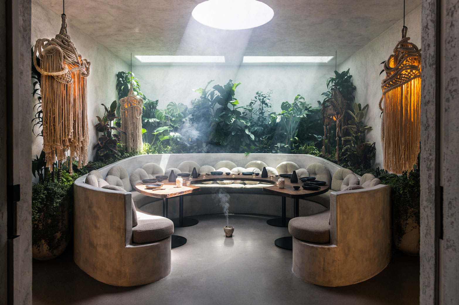 shot of a crescent-shaped banquette surrounded by plants in meteora's private dining room